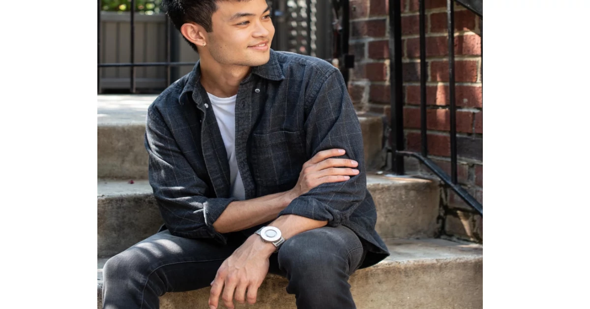 Homem sentado nas escadas a sorrir com um Bradley no pulso