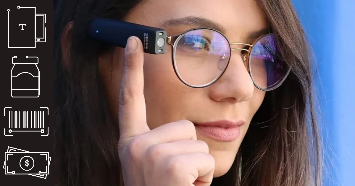Senhora utiliza o Leitor Orcam MyEye encaixado na haste dos óculos. Aponta para indicar a leitura.